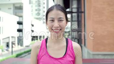 健康美丽的年轻亚洲跑步女子在城市的街头跑步后，感到快乐的微笑和寻找相机。